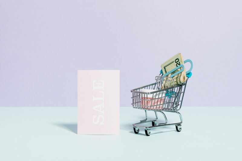 A small shopping trolley sits next to a 'Sale' sign, used to exemplify the cost of living crisis